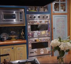 a kitchen with an oven, microwave and table in front of the counter top is decorated with flowers