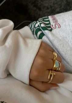 a person with two rings on their fingers and one is wearing a white shirt, while the other has a gold ring