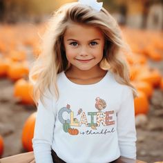 Long Sleeve Toddler Thanksgiving Shirt for boys or girls. A delightful and personalized garment that will bring extra joy to your child's Christmas. This charming Thanksgiving t-shirt displays your child "is thankful," capturing the essence of the thanksgiving season. But what makes it truly special is the adorable turkey, pumpkins and falling leaves that surround your child's name. Each t-shirt is personally and uniquely designed. It's a whimsical scene that will ignite the imagination and fill Personalized Cotton T-shirt For Fall, Customizable Cute Tops For Fall, Cute Name Print Tops For Fall, Cute Tops With Name Print For Fall, Casual Personalized T-shirt For Fall, Personalized Casual T-shirt For Fall, Long Sleeve Name Print Tops For Fall, Long Sleeve Tops With Name Print For Fall, Toddler Thanksgiving Shirt