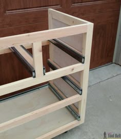 a wooden shelf with drawers on top of it in front of a garage door that is being built