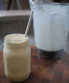 a mason jar with a straw in it sitting on a table next to a blender