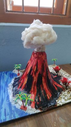 a cake made to look like a volcano with clouds and trees on the top, sitting on a table