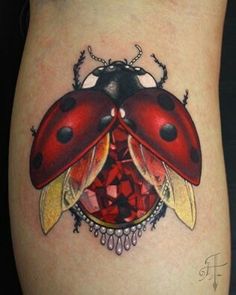 a ladybug tattoo on the side of a woman's leg with diamonds