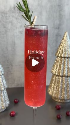 a glass filled with red liquid next to christmas trees