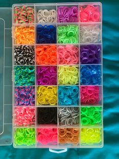 a box filled with lots of different colored rubber bands on top of a blue blanket