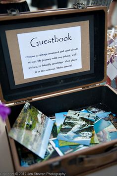 an open suitcase filled with pictures and cards on top of a table next to flowers