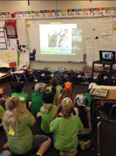 a group of children sitting in front of a projector screen