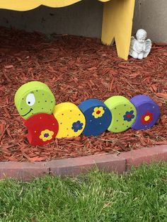 a toy train that is sitting on the ground in front of some grass and flowers