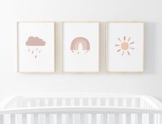 three framed pictures hang on the wall above a crib in a white nursery room