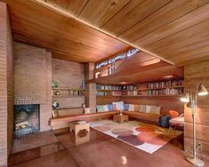 a living room with wooden walls and flooring is shown in this image, there are bookshelves on either side of the fireplace