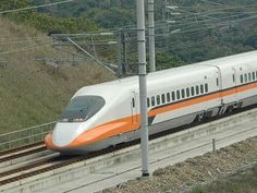 an orange and white train traveling down tracks