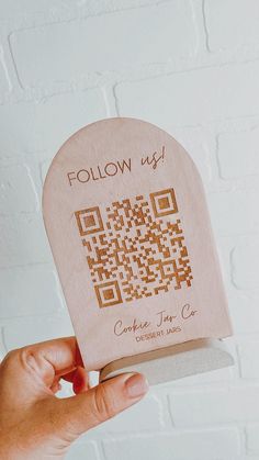 someone holding up a piece of wood with a qr code printed on the front