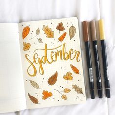 an open notebook with the word november written in gold on it next to three markers