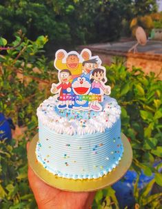 a hand holding a cake with cartoon characters on it