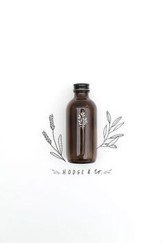 a brown glass bottle sitting on top of a white table next to a drawing of leaves