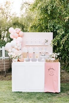 a pink and white dessert bar with balloons