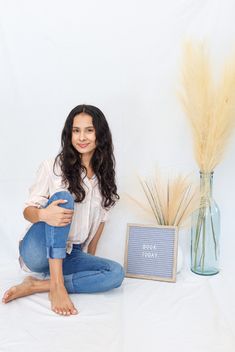 a woman is sitting on the floor with her legs crossed and holding a blue ball