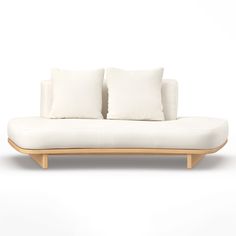 a white couch sitting on top of a wooden frame next to two pillow pillows in front of a white wall