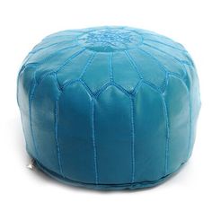 a blue leather poufle with stitching on the top and bottom, sitting on a white surface