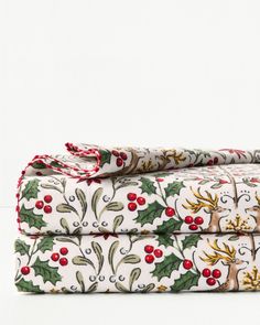 two sheets with holly and reindeer designs on them, one is folded up to the side