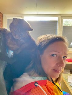 a woman holding a cat in her arms and looking at the camera with an intense look on her face