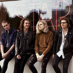 four young men sitting on a window sill in front of a sign that says cat's cafe