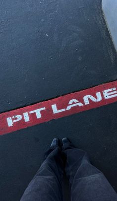 a person standing in front of a red street sign that says pitt lane on it