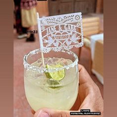 a hand holding a glass with a drink in it and a paper cutout on the top