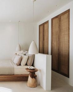 a bed sitting next to a white wall in a room with wooden doors and windows