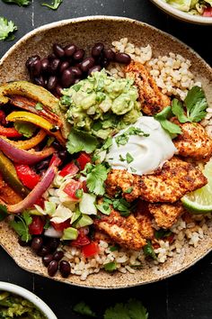 a bowl filled with chicken, rice and veggies on top of a table