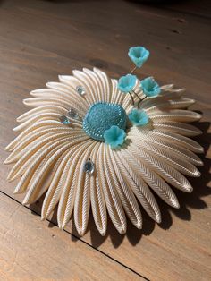 a brooch that is sitting on top of a wooden table with flowers in it