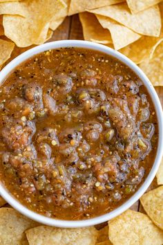 a white bowl filled with salsa surrounded by tortilla chips