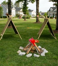 a fire pit in the middle of a yard with two teepees on it