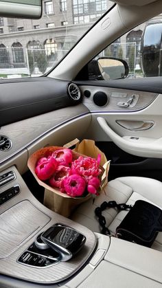 a bouquet of pink flowers sitting in the center console of a car