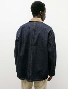 An oversized loose fitting worker coverall jacket cut from a midweight "one-wash" rinsed indigo denim. features a contrasting collar in beige corduroy tack buttons at the closure four utility pockets at the front a large internal patch pocket and functional engineer's cuffs. the generous cut offers a pleasing amount of volume throughout the silhouette tending to billow out through the back and is complemented by the gentle forward stance of a two piece sleeve. constructed with orslow's trademark attention to durability using triple needle chain stitched flat felled seams and riveted reinforcements throughout for a hard wearing finish that is built to last; silver tone logo stamped hardware classic golden contrast stitching throughout.    - made in japan  - 100% cotton; contrast: 80% cotton Dark Wash Selvedge Outerwear For Work, Flat Felled Seam, Utility Pockets, Indigo Denim, Logo Stamp, Chain Stitch, Contrast Stitch, Made In Japan, Patch Pocket