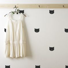 a white dress hanging on a wall with black cat decals