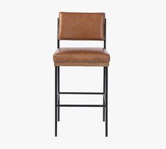 a brown leather bar stool against a white background with the seat upholstered in black metal