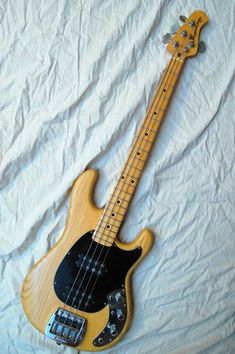 an electric bass guitar laying on top of a white sheet