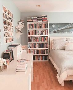 a bed sitting next to a white book shelf filled with books on top of a hard wood floor