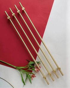 four gold colored metal straws sitting on top of a red and white table