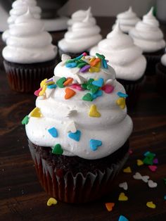 cupcakes with white frosting and sprinkles on a wooden table