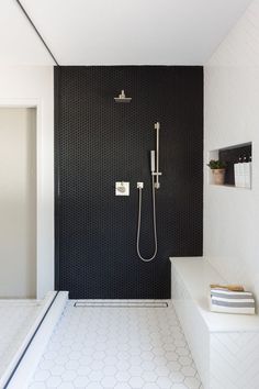 a black and white bathroom with hexagonal tiles on the floor, shower head, and bench