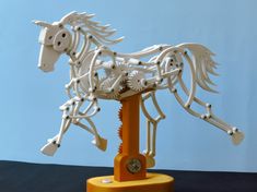 a white horse made out of plastic parts on a stand with wheels and gears attached to it