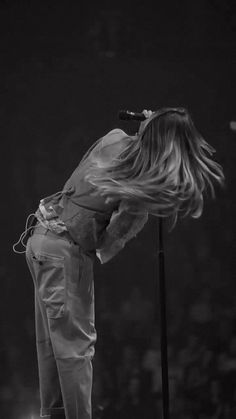 a woman standing on top of a stage with her hair blowing in the wind while holding a microphone