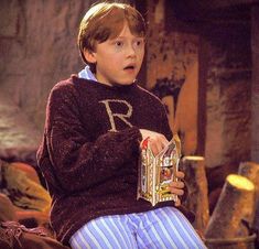 a young boy in a sweater holding a box with the letter r on it and looking surprised