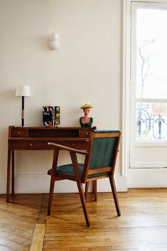 a desk with a chair, lamp and pictures on it