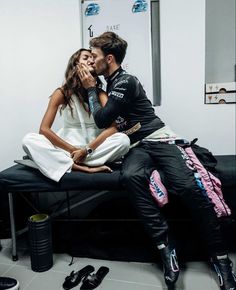 a man and woman kissing while sitting on a bed