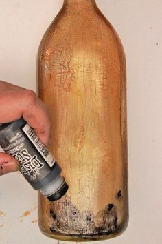 a person is painting a bottle with brown paint