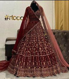 a red bridal gown on display in front of a couch