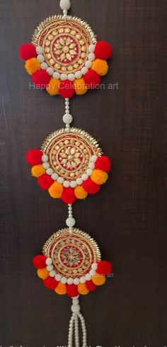 two decorative wall hangings with red, yellow and white pom poms